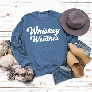 Flat lay of indigo Whiskey Weather sweatshirt with autumn accessories on white wood