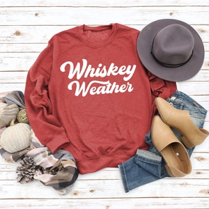 Flat lay of dark red Whiskey Weather sweatshirt with autumn accessories and decor