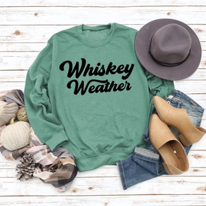 Flat lay of light green Whiskey Weather sweatshirt with autumn accessories on wood background