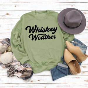 Flat lay of green Whiskey Weather sweatshirt with autumn accessories on white wood