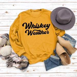 Flat lay of mustard yellow 'Whiskey Weather' sweatshirt with autumn lifestyle accessories