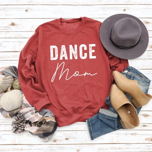 Flat lay of red Dance Mom sweatshirt with autumn accessories on white wood floor