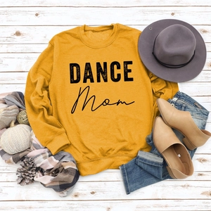 Flat lay of mustard crewneck sweatshirt with black DANCE MOM print and autumn accessories
