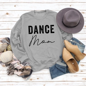 Flat lay of gray DANCE MOM sweatshirt styled with autumn accessories on wood background