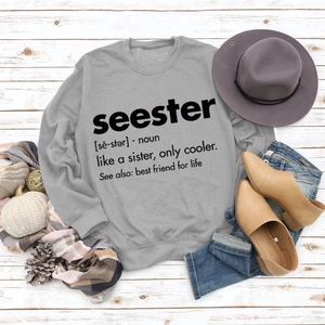 Flat lay of grey crewneck sweatshirt with Seester print on white wooden floor