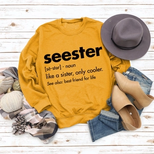 Flat lay of ginger yellow crewneck sweatshirt with Seester letter print and autumn props
