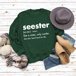 Flat lay of green Seester printed sweatshirt with autumn accessories on white wood