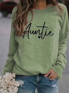 Close-up of sage green sweatshirt featuring black Auntie text and a small heart