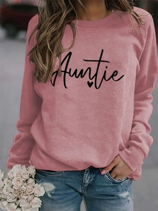Close-up of black Auntie text and heart print on pink crewneck sweatshirt fabric