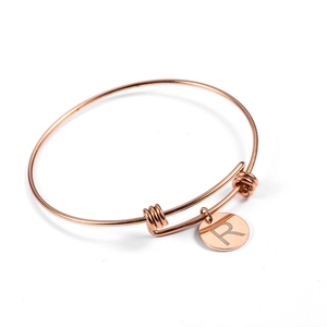 Close-up of rose gold adjustable wire bracelet with circular initial R letter charm