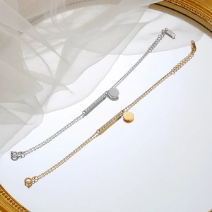 Minimalist gold and silver titanium steel bracelets with bar and disc pendants on mirror