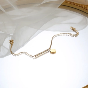 Elegant gold titanium steel bracelet featuring a crystal bar and circular pendant on mirror