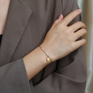 Close-up of gold titanium steel bracelet with pavé zirconia bar and round pendant