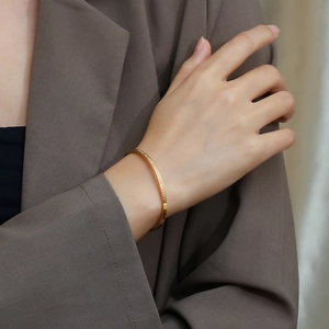 Close-up of golden stainless steel cuff bracelet with engraved inspirational quote
