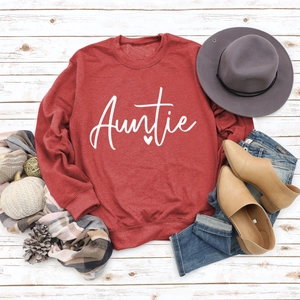 Flat lay of red Auntie sweatshirt with blue jeans, autumn hat and plaid scarf accessories