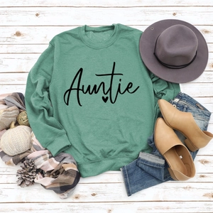 Flat lay of green crewneck Auntie sweatshirt with autumn lifestyle props on wood