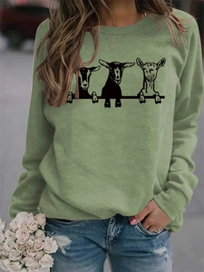 Détail du sweat-shirt vert avec trois imprimés de chèvres amusants porté par un mannequin