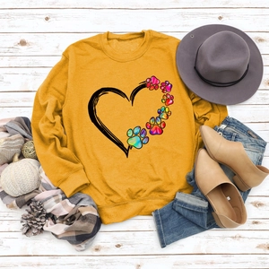 Close-up of mustard yellow sweatshirt with rainbow heart and dog paw print detail