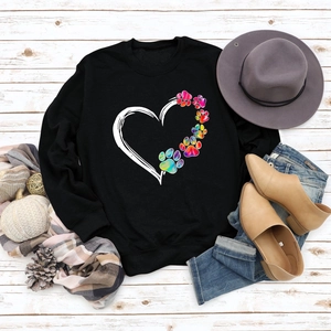 Flat lay of black sweatshirt with rainbow paw heart print and autumn accessories