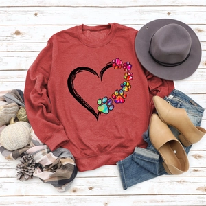 Detail of red crewneck sweatshirt featuring artistic heart and dog paw prints