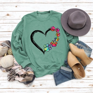 Flat lay of bean green sweatshirt with heart and rainbow dog paw print and autumn accessories