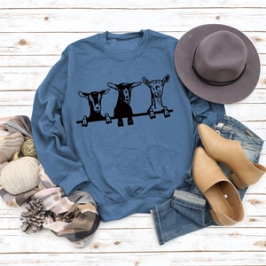 Sweat bleu à col rond avec motif alpaga présenté sur un fond en bois rustique