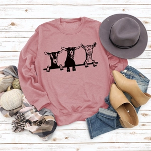 Mise à plat d'un sweat rose à motif alpaga avec jean et écharpe sur fond en bois
