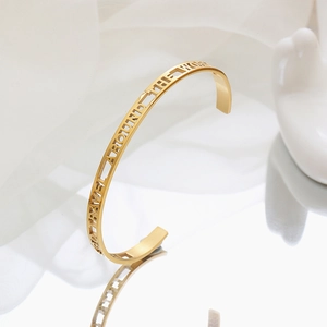 Adjustable gold cuff bracelet featuring cutout lettering Go Travel Around The World