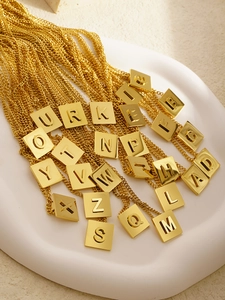 Nahaufnahme der goldenen quadratischen Buchstabenanhänger A-Z auf weißem Tablett