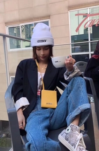 Streetstyle-Look mit Model, das eine Buchstaben-Halskette zu Blazer und Jeans trägt