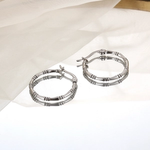 Polished silver bamboo-style stainless steel hoop earrings on minimalist white background