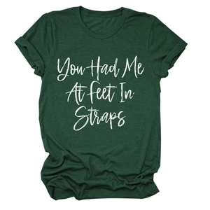 Dettaglio della stampa You Had Me At Feet In Straps su maglietta verde scuro con maniche risvoltate