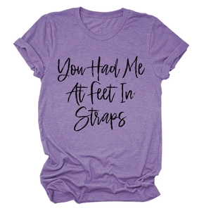 Dettaglio della t-shirt viola con stampa You Had Me At Feet In Straps e maniche arrotolate