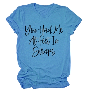 Dettaglio della t-shirt girocollo azzurra con slogan nero You Had Me At Feet In Straps