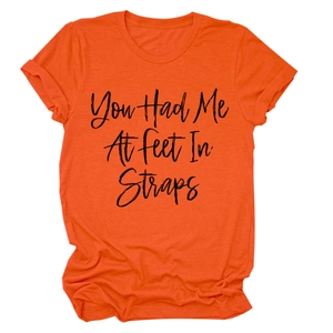 Dettaglio della t-shirt arancione a girocollo con stampa You Had Me At feet In Straps