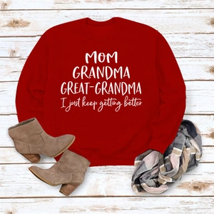 Vue à plat d'un sweat-shirt rouge avec imprimé MOM GRANDMA sur fond bois blanc