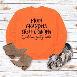 Gros plan du sweat orange avec texte imprimé MOM GRANDMA GREAT et accessoires d'automne