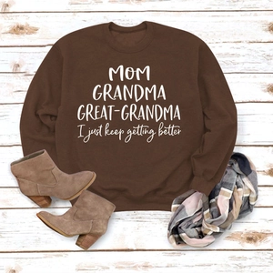 Détail d'un sweat marron avec imprimé Mom Grandma Great-Grandma sur fond en bois