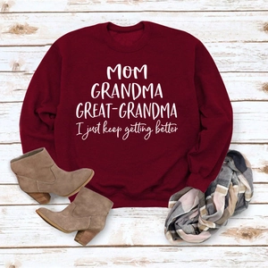 Mise à plat d'un sweat bordeaux avec lettrage blanc sur un fond en bois rustique
