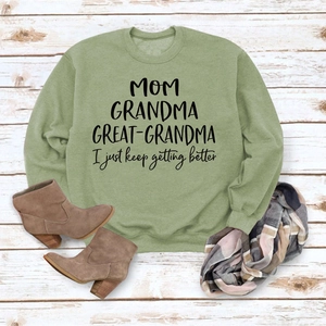 Mise à plat du sweat à col rond vert clair avec texte MOM sur un sol en bois blanc