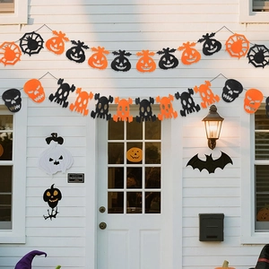 Halloween felt banners with bats and pumpkins hanging on a white wooden house wall