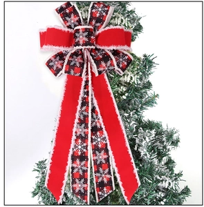 Macro detail of red and black plaid Christmas bow with white snowflake prints and fuzzy edges