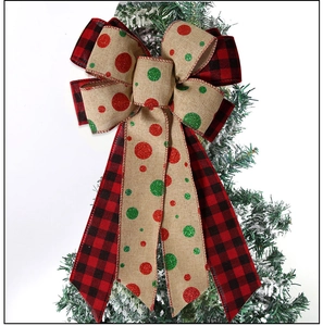 Detail of red buffalo plaid and linen Christmas bow with sequins on a snowy branch