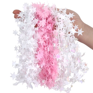 Detail of pink and white tinsel garlands with star shapes held by hand for Christmas decor