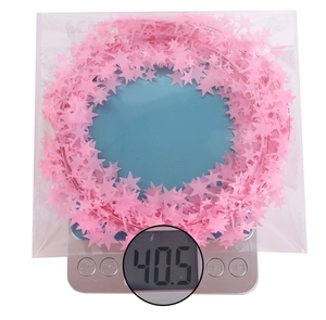 Detail shot of 7.5m pink star tinsel garland being weighed on a scale for quality check