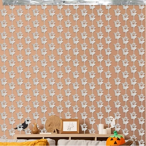 Vertical white ghost paper garland hanging against orange wall for Halloween party decor