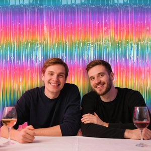 Regenbogen-Folienvorhang als Party-Hintergrund mit feiernden Gästen bei einer Feier