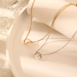 Elegant gold and silver titanium necklaces with planet pearl pendants on white plate
