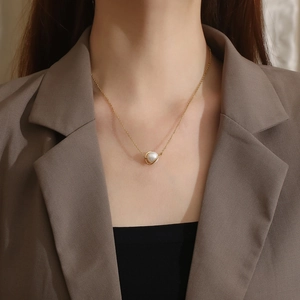 Close-up of pearl Saturn pendant on golden titanium steel chain necklace on model