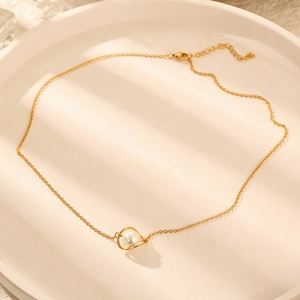 Detail of elegant gold planet pearl pendant on a thin chain with lobster clasp closure